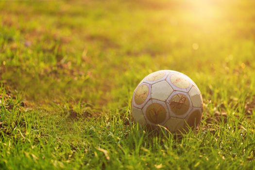 old soccer ball on green grass field with morning light