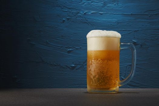 Beer in mug on table with rough blue background