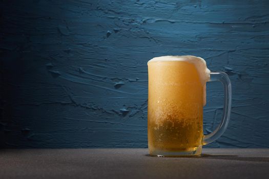 Beer in mug on table with rough blue color background