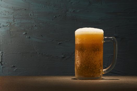 Cold beer in mug on table with rough background