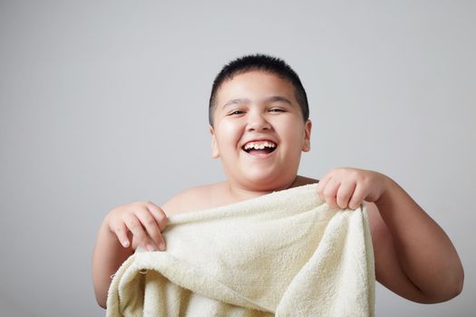 An Asian teenage boy smiles brightly with his towel.