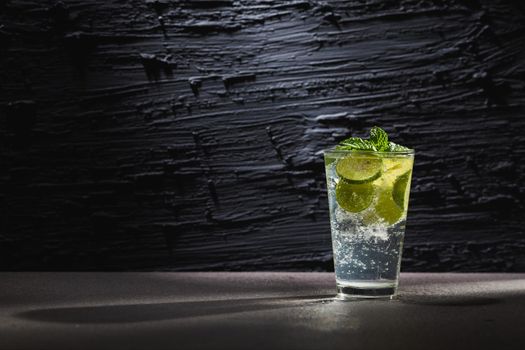Mojito cocktail with lime and mint in  glass with ice on a dark background