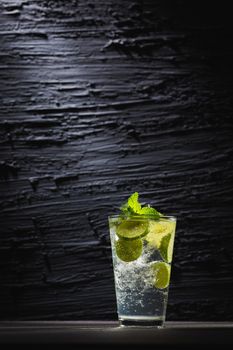 Mojito cocktail with lime and mint in  glass with ice on a dark background