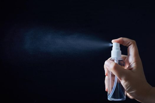 Alcohol spray bottle with diffusing mist on dack background, Alcohol for disinfection