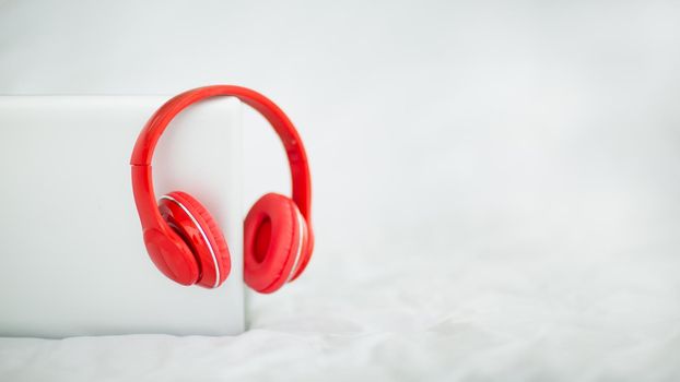 Headphones are placed on the computer on the white bed. For online learning and video conferencing meetings