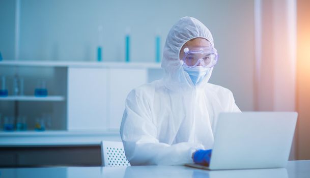 Medical scientists in protective clothing are analyzing experimental data on computers in the laboratory.