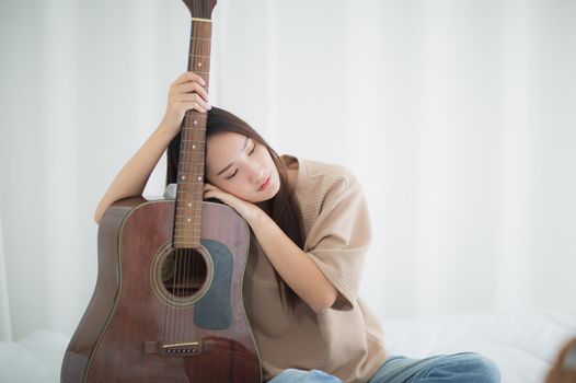 Asian woman Sad hug guitar in home