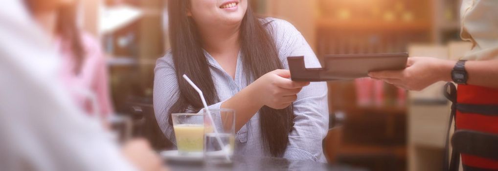 Woman and friend smiling and happy to pay the bill in the restaurant. Banner size photo