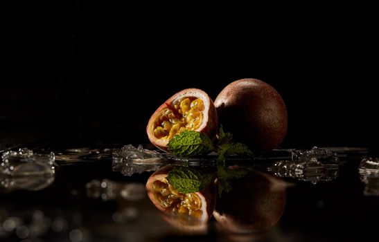 Passion fruit sliced on dark background with reflection.