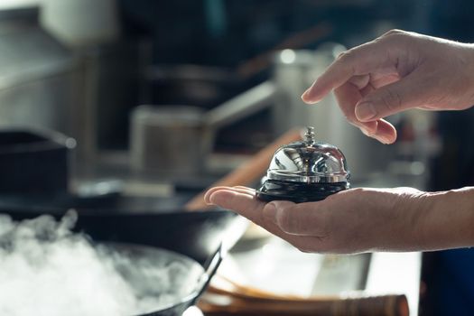 Bell of service for food on hand with kitchen background