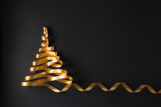 Christmas tree made of gold ribbon  on black background