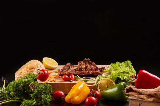 Grilled steaks and mixed vegetables on dark background