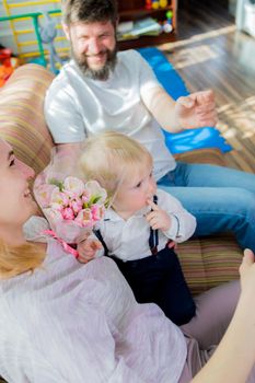 Dad with children congratulate mom on the holiday, mother's day. Have fun, laugh and give flowers