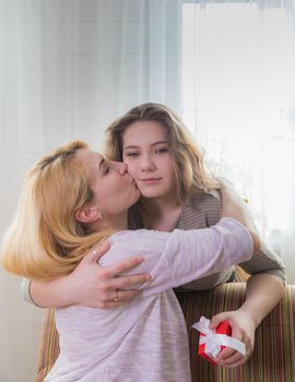 A young girl congratulates her mother on the holiday. Hugs gently and smiles.