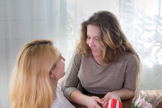 A young girl congratulates her mother on the holiday. Hugs gently and smiles.