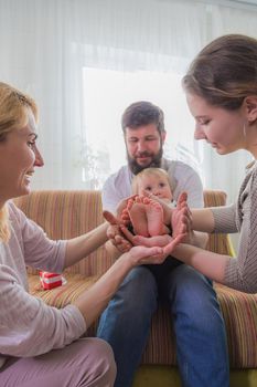 The whole family, parents and children hold the baby's heels in the palms of the hands.