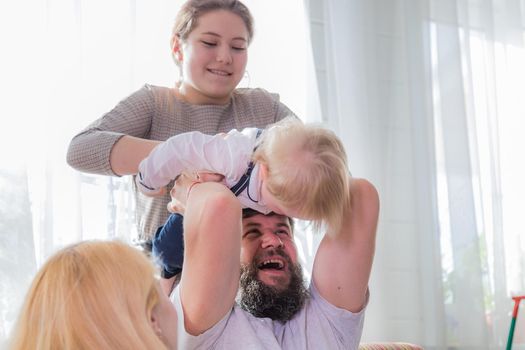 Dad and daughter play with the baby, holding him on his head. Mother's day holiday