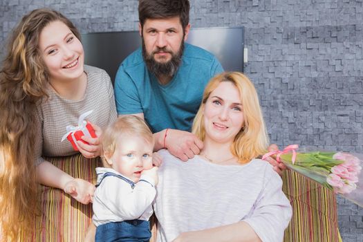 Dad with children congratulate mom on the holiday, mother's day. Have fun, laugh and give flowers