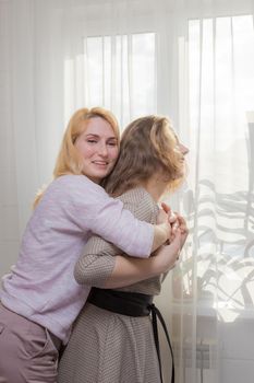 A young girl congratulates her mother on the holiday. Hugs gently and smiles.