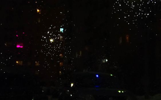 Reflection in a glass of glass. Blurred fires of distant houses. Window.