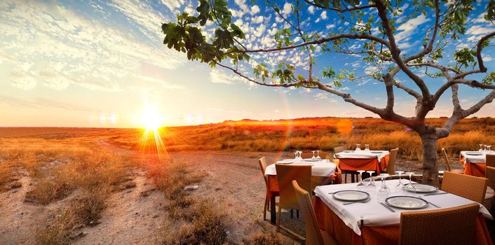 Surreal sunset landscape with table with dishes in romantic and idyllic nature.
