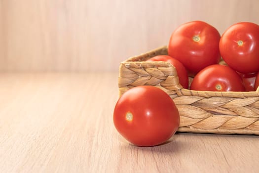 red ripe tomatoes in a basket on a light background. High quality photo