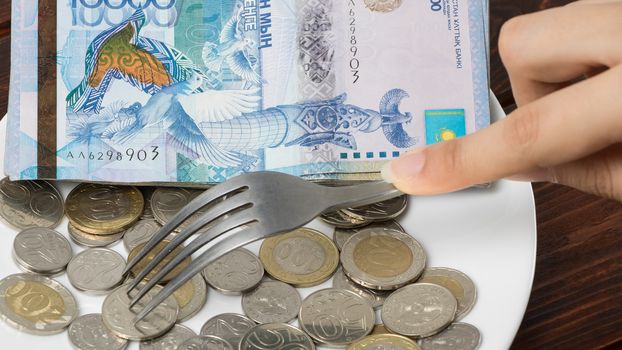 Kazakhstani tenge on a plate on the table. The national currency of Kazakhstan. Salary in tenge. Grocery basket, budget savings. Divide the budget.