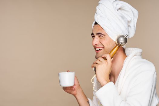Happy man talking on the phone with a cup of coffee and a towel on his head.