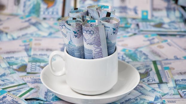 Kazakhstan tenge in a Cup on the table.A lot of Kazakh money.Sawing the budget,the subsistence minimum or the dual currency basket in Kazakhstan.The crisis by the fall in exchange rates