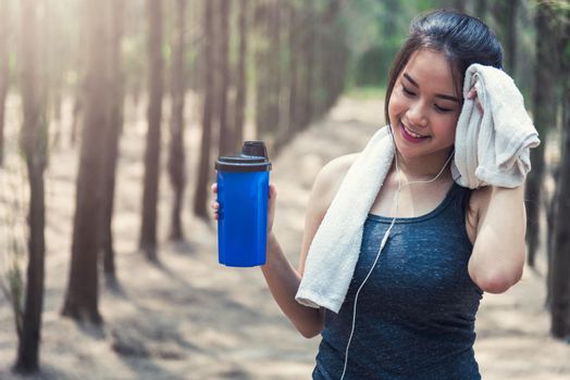Sport beautiful young woman girl lifestyle exercise healthy drinking water after running  workout in forest nature park with copy space