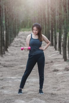 Sport young woman girl lifestyle exercise holding fitness dumbbell workout in forest nature park with copy space