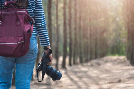 Young woman lifestyle using DSLR camera photographer travel taking photo in forest nature park and backpack and copy space