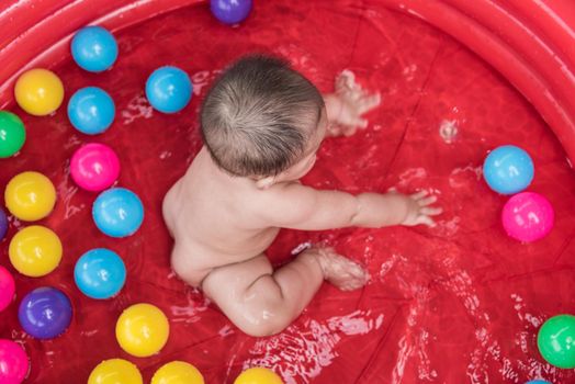 Asia Baby Child Relaxing in swimming pool, with colorful balls