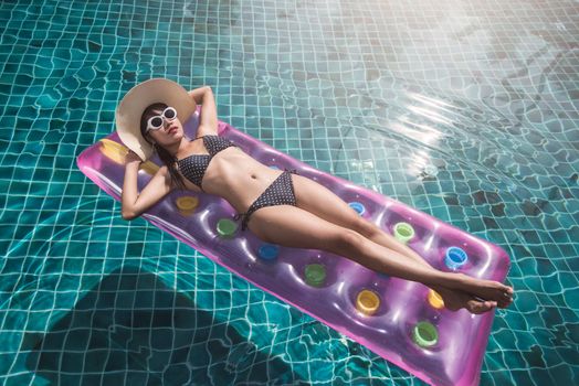 Young woman in bikini swimming pool on mattress inflatable, vacation summer holiday concept