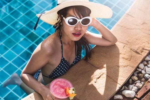 Young woman in bikini luxury swimming pool drink cocktail, vacation summer holiday concept