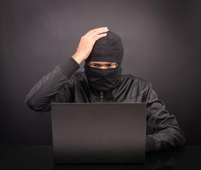 Computer hacker dizziness or headache - Male thief stealing data from laptop computer on black background