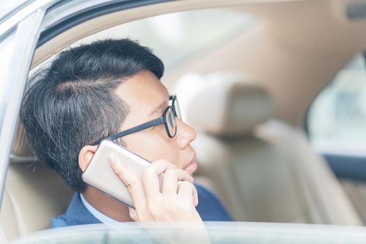 Young asian business men portrait in suit working in the backseat of a car