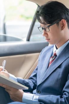 Young asian business men portrait in suit working in the backseat of a car