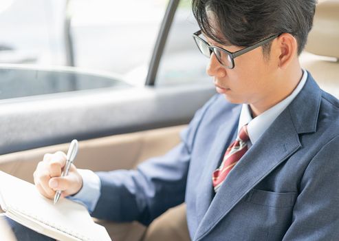 Young asian business men portrait in suit working in the backseat of a car