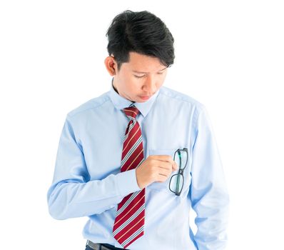 Male wearing blue shirt and red tie holding eyeglasses isolated on white background