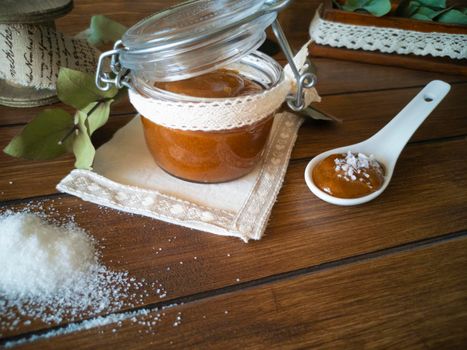 Dulce de leche typical dessert of chocolate and milk cream with vanilla beans, greedy for the sweet temptation of sugar. Copy space wooden background with glass jar full of brown cream and spoon