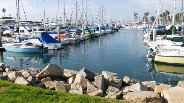 Oceanside, California USA - 27 Jan 2020: Waterfront harbor fisherman village, luxury yachts sailboats floating, marina harbour quay. Sail boat masts, nautical vessels anchored or moored in port.