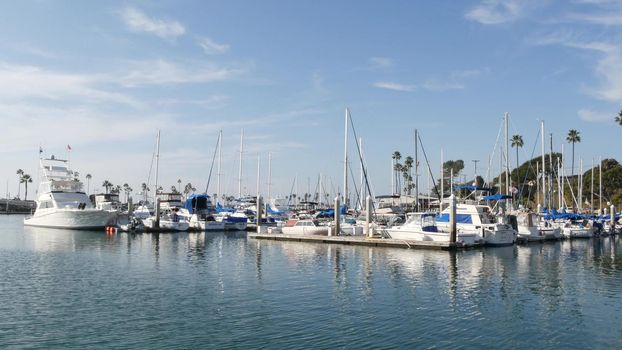 Oceanside, California USA - 27 Jan 2020: Waterfront harbor fisherman village, luxury yachts sailboats floating, marina harbour quay. Sail boat masts, nautical vessels anchored or moored in port.