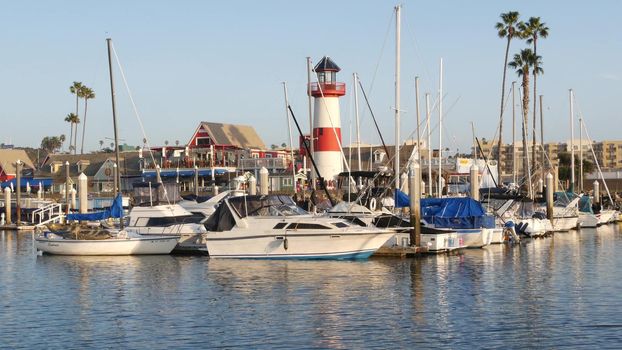 Oceanside, California USA - 27 Jan 2020: Waterfront harbor fisherman village, yachts sailboats floating, marina harbour quay. Sail boat masts, nautical vessels moored in port, lighthouse or beacon.