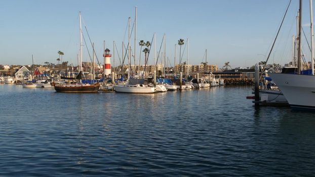 Oceanside, California USA - 27 Jan 2020: Waterfront harbor fisherman village, yachts sailboats floating, marina harbour quay. Sail boat masts, nautical vessels moored in port, lighthouse or beacon.