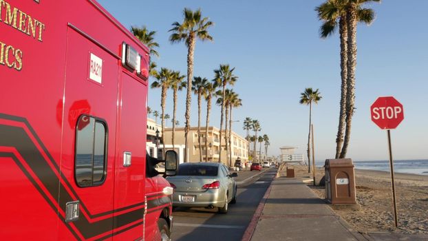 Oceanside, California USA - 11 Feb 2020: EMS emergency medical service red vehicle by ocean beach. Fire department ambulance car. Lifeguard paramedic rescue truck on beachfront road. 911 public safety