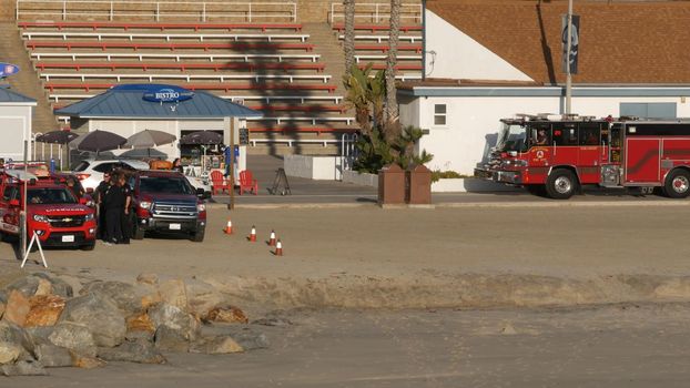 Oceanside, California USA -11 Feb 2020: Red fire engine by ocean beach near Los Angeles. Firefighters vehicle or truck, american Fire Department car. 911 public safety. Firetruck and lifeguard pick up