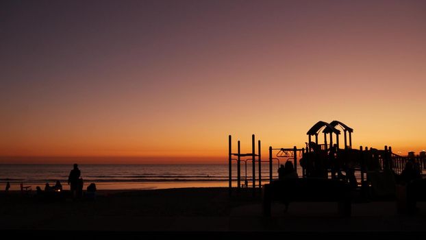 Oceanside, California USA - 8 Feb 2020: Silhouette of people making bbq campfire. Beachfront recreation area for barbeque with fire place on pacific ocean coast. Bonfire for barbecue on sunset beach.