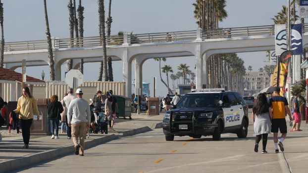 Oceanside, California USA - 8 Feb 2020: American police department patrol car, squad, interceptor or cruiser, 911 auto, public safety vehicle on beach. City near Los Angeles. People walking near pier.