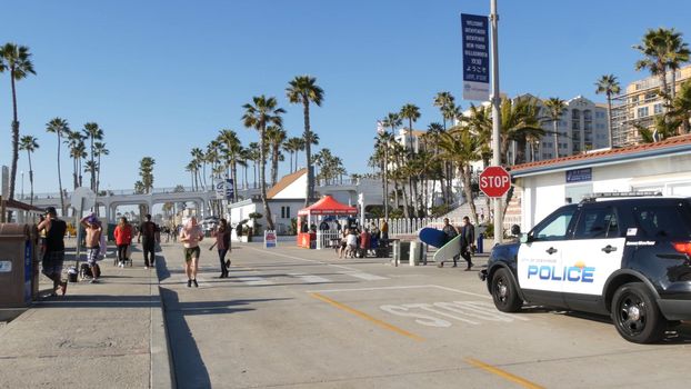 Oceanside, California USA -16 Feb 2020: American police department patrol car, squad, interceptor or cruiser, 911 auto, public safety vehicle on beach. City near Los Angeles. People walking near pier.